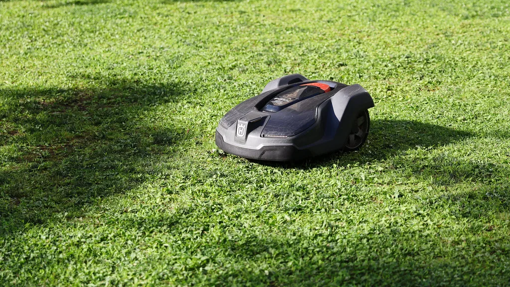 Un robot tondeuse noir au milieu d’un gazon court